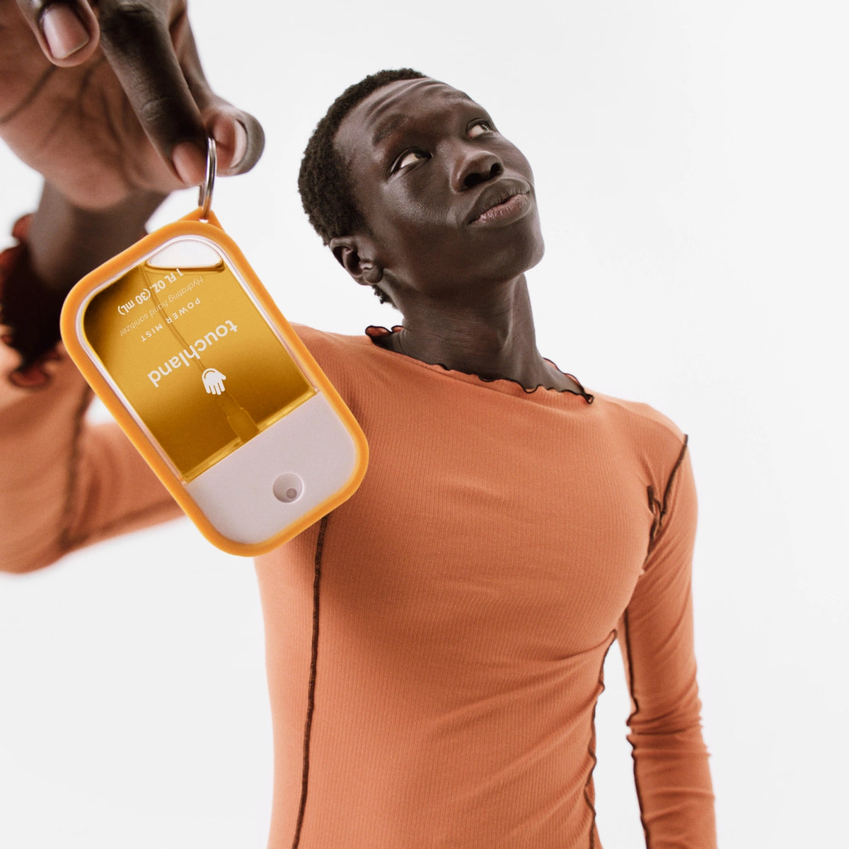 Person wearing an orange long-sleeve shirt with a keychain attached, on a white background