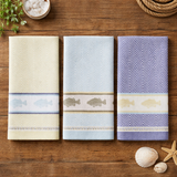 Three patterned towels on a wooden surface with decorative items.