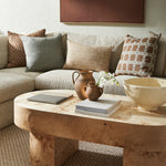 Living room with a beige sectional sofa, wooden coffee table, and decorative items.