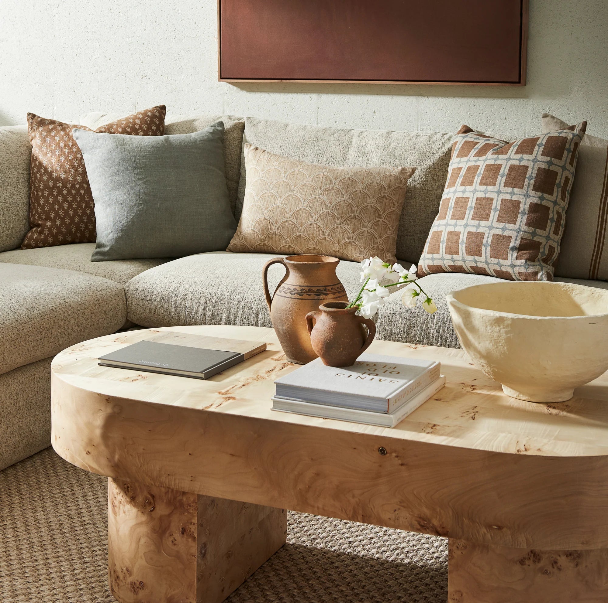 Living room with a beige sectional sofa, wooden coffee table, and decorative items.