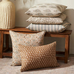 Patterned pillows on a wooden bench against a neutral wall.