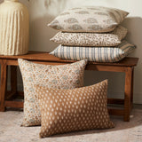 Patterned pillows on a wooden bench against a neutral wall.