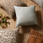 Patterned cushions on a textured surface with a plant and leather item.