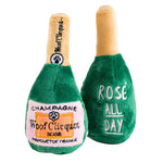 plush dog toys shaped like a champagne bottle saying "woof clicquot" and "rose all day"