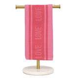Pink towel with 'LOVE' text on a gold towel rack against a white background