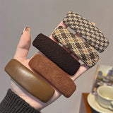 Hand holding five textured hair clips in various colors against a neutral background