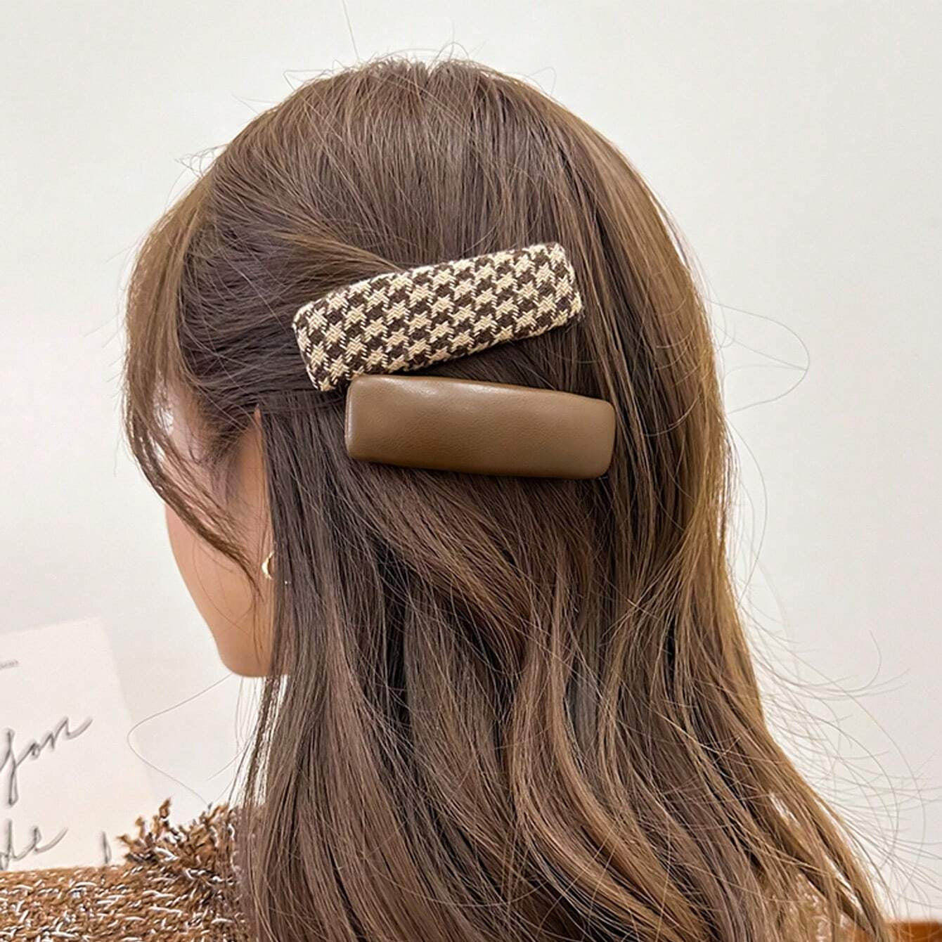 Woman with long brown hair wearing a houndstooth patterned hair clip.