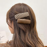 Woman with long brown hair wearing a houndstooth patterned hair clip.