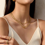 Woman wearing a gold necklace and ring with a neutral background