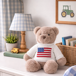 Teddy bear wearing an American flag sweater on a dresser with toys and decor.