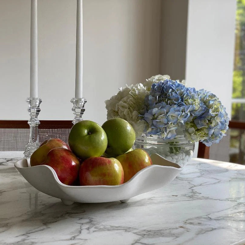 Bowl of apples and flowers on a marble countertop