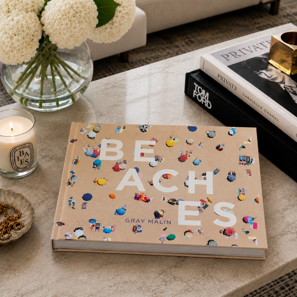 Book titled 'Beaches' by Gray Malin on a coffee table with decor items.