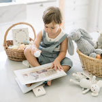 Child reading a book with toys around in a bright room