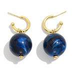 Gold hoop earrings with blue spherical beads on a white background