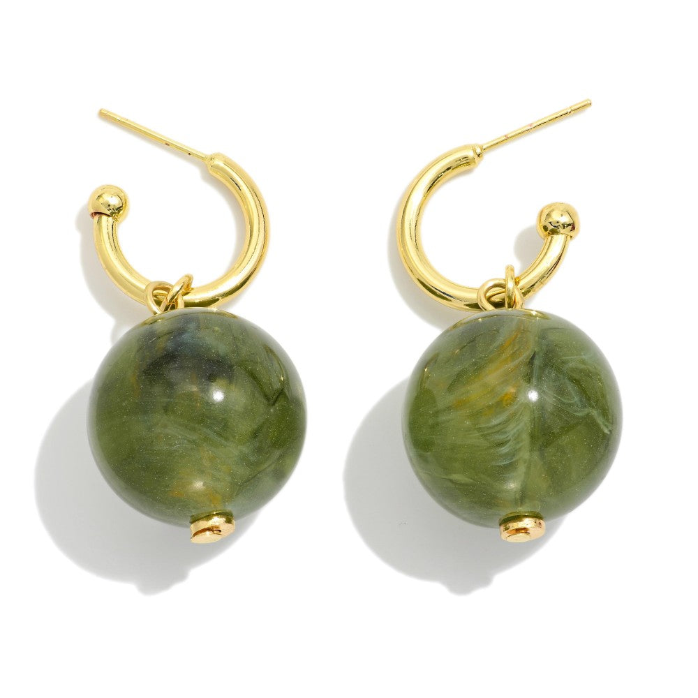 Gold hoop earrings with green spherical stones on a white background