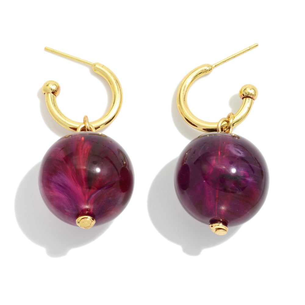 Gold hoop earrings with purple marbled beads on a white background