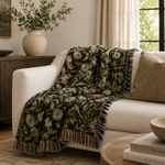 Floral-patterned throw blanket draped over a white sofa in a living room setting.