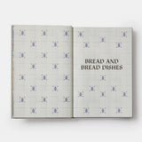 Open book with a patterned cover titled 'Bread and Bread Dishes' on a white background