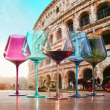 Five colorful wine glasses in front of the Colosseum in Rome.