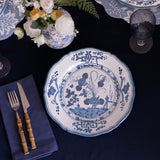 beatriz ball vida faenza 11" dinner plate on a dark tablecloth with floral arrangement and cutlery.