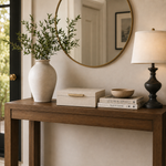 Wooden console table with decorative items including a vase, books, and a lamp in a room setting.