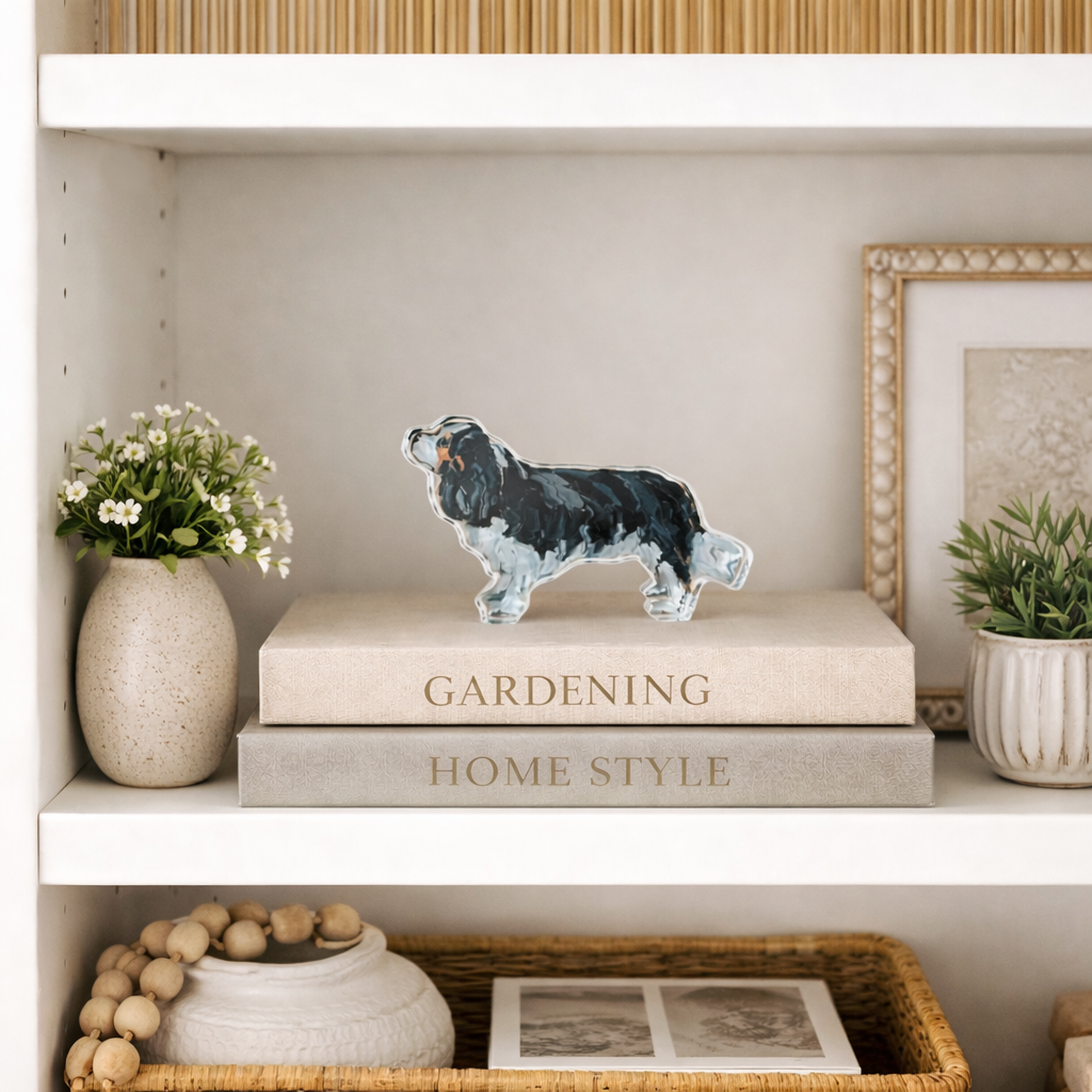 Decorative shelf with books, a figurine of a dog, and plants.