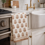 Patterned towel hanging on a kitchen oven handle with a sink and faucet in the background.