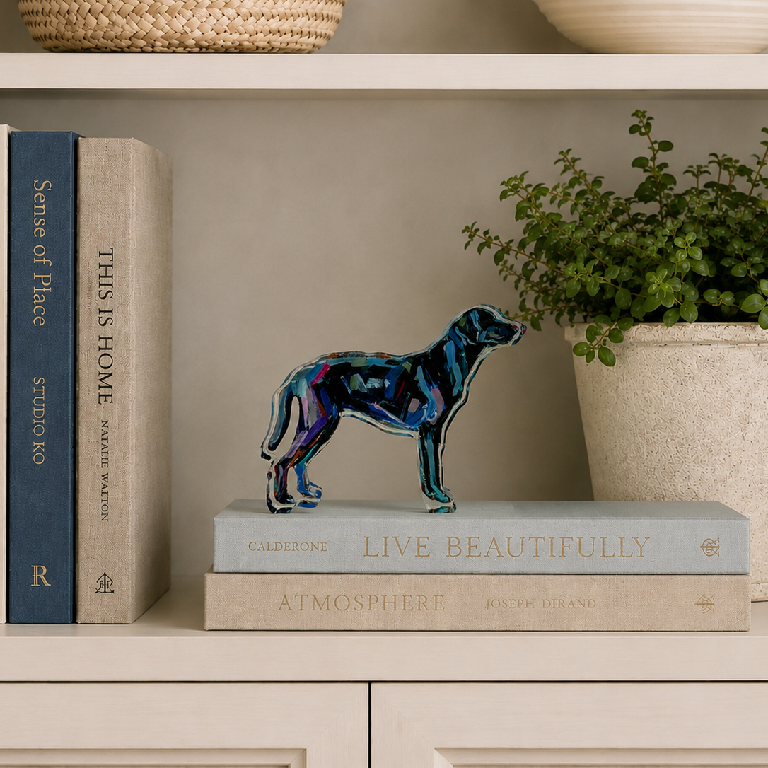 Decorative bookshelf with books, a colorful dog sculpture, and a plant.