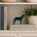 Decorative bookshelf with books, a colorful dog sculpture, and a plant.