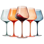 Five wine glasses of different colors with varying levels of red wine on a white background