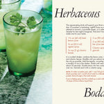 Two green cocktails with herbs on a marble surface, accompanied by a recipe card titled 'Herbaceous' from a magazine.