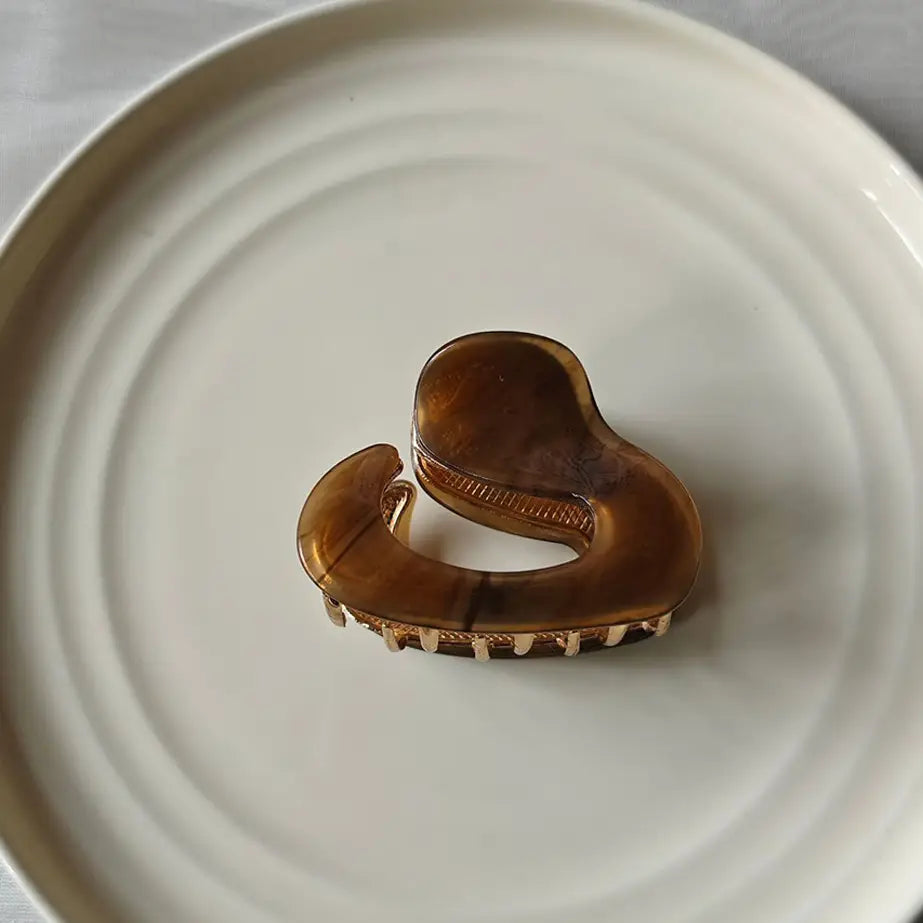 Brown tortoiseshell hair claw on a white ceramic plate