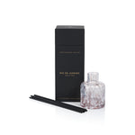 Aromatherapy diffuser set with a black box, glass diffuser bottle, and black sticks on a white background.