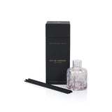 Aromatherapy diffuser set with a black box, glass diffuser bottle, and black sticks on a white background.