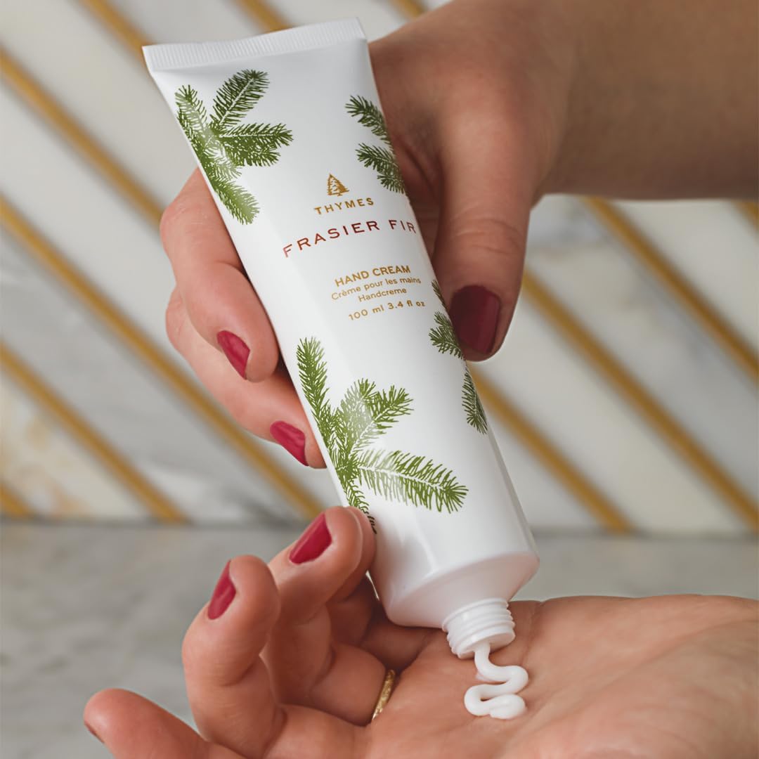 Hand applying Thymes Frasier Fir hand cream to another hand with a blurred background