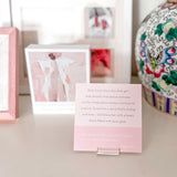 Pink card with text on a stand, framed pictures in the background