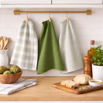 Kitchen counter with bread, a bowl of fruit, and checkered towels hanging on a rack.