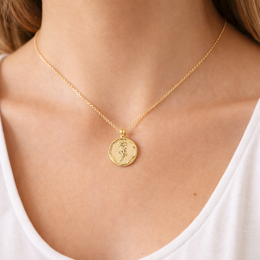Gold necklace with a pendant on a person wearing a white top