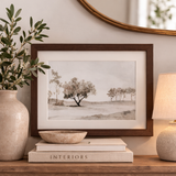 Framed landscape print on a shelf with decorative items