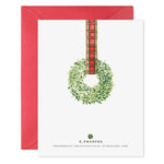 Greeting card with a green wreath and plaid ribbon on a white background with a red envelope.
