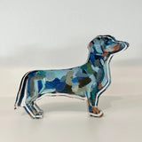 Clear acrylic dachshund dog shelfie with abstract blue and teal painted artwork encased in a thick freestanding block on a white background.