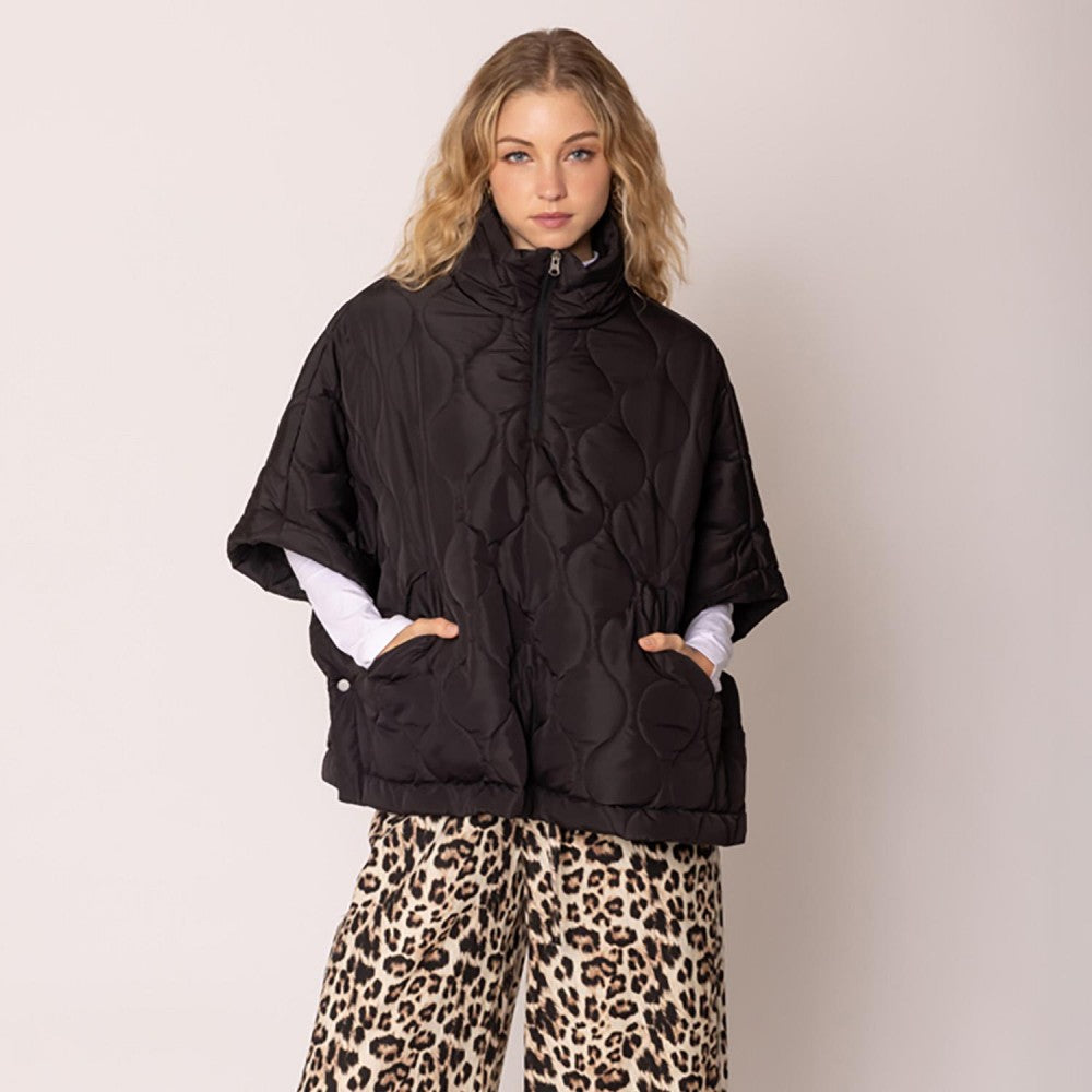 Woman wearing a black quilted jacket and leopard print pants on a beige background