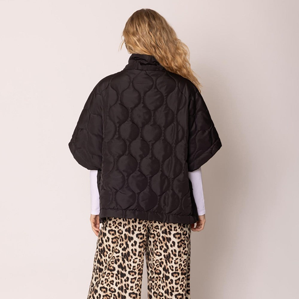 Person wearing a black quilted jacket and leopard print pants on a plain background