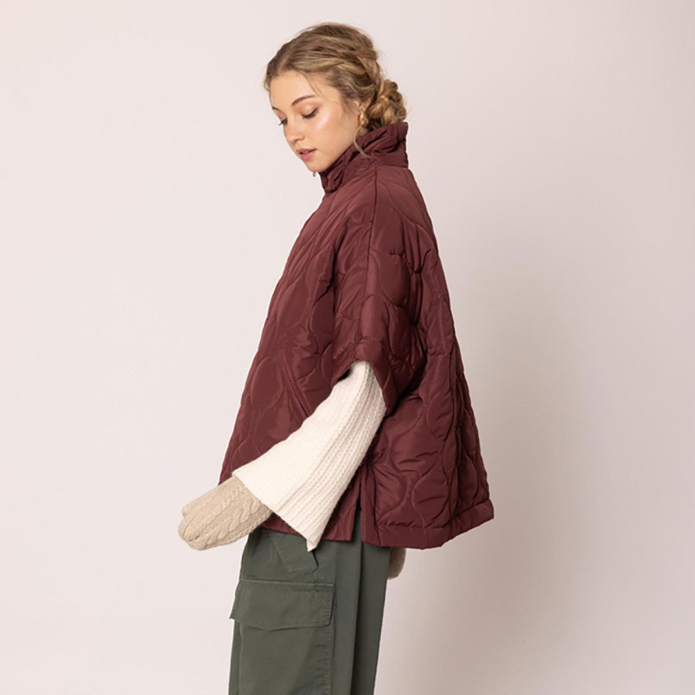 Woman wearing a burgundy puffer jacket on a plain background