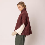 Woman wearing a burgundy puffer jacket on a plain background