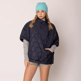 Person wearing a navy blue quilted jacket and light blue beanie on a plain background