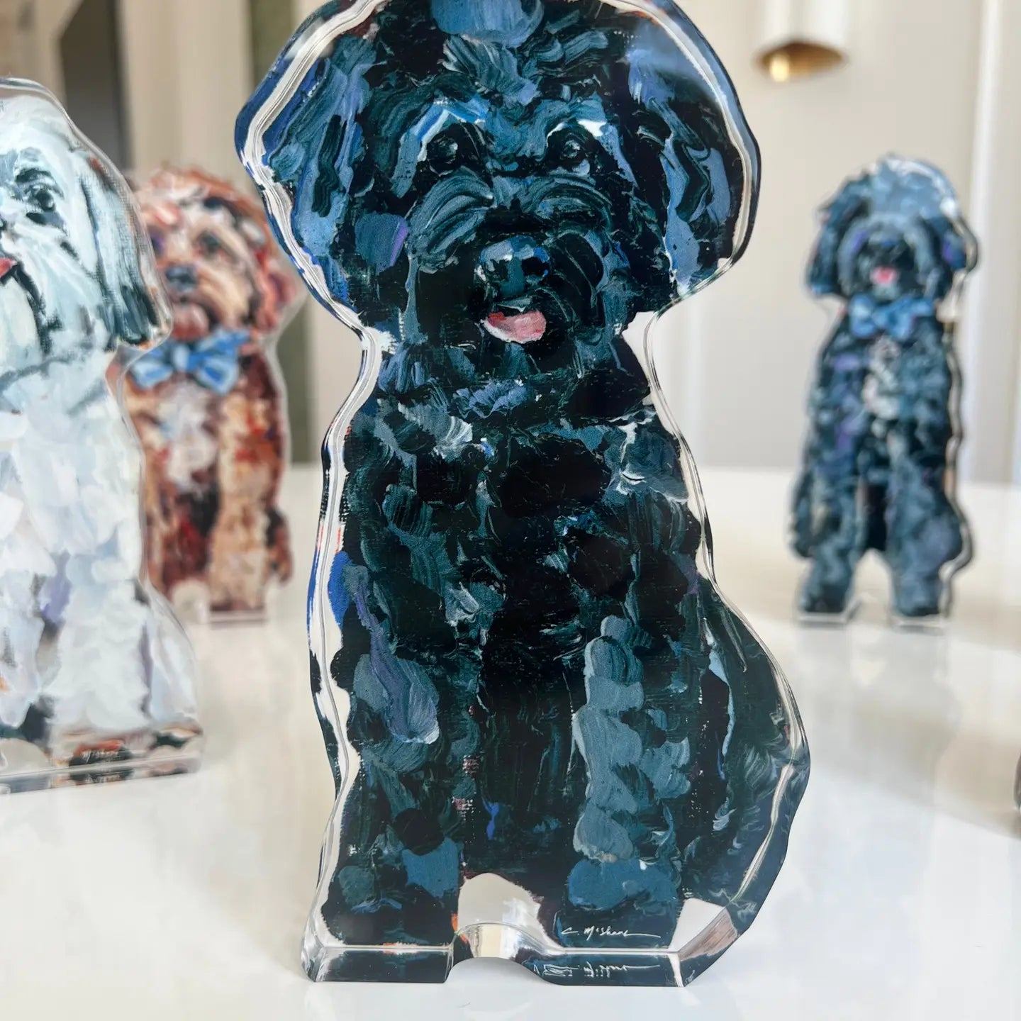 Clear acrylic standee of a black dog with blue accents on a white surface.