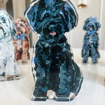 Clear acrylic standee of a black dog with blue accents on a white surface.