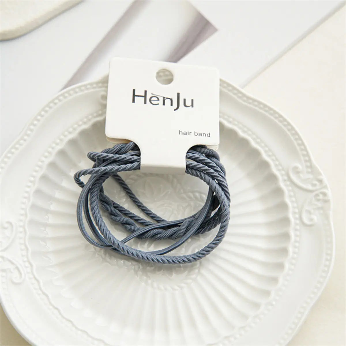 Three gray hair bands on a white plate with a HenJu label.