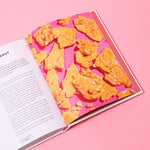 Book with a pink cover featuring a pattern of orange snacks on a pink background